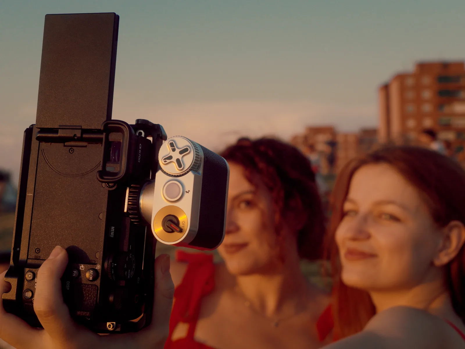 Camera in the foreground against a sunset sky fading from blue to orange, with blurred Madrid buildings behind
