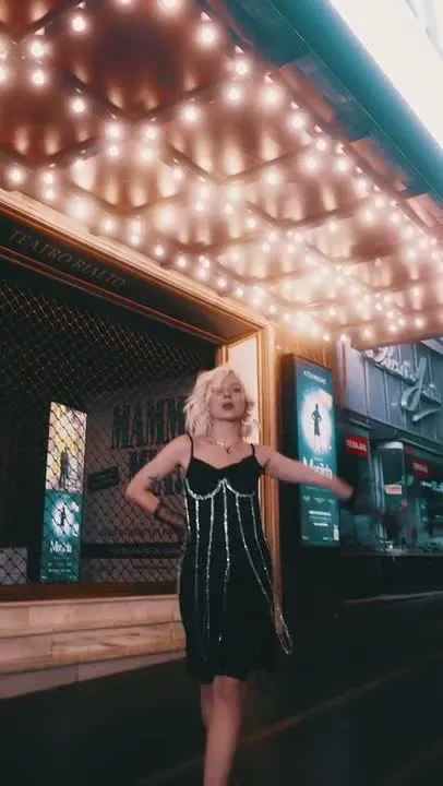 Modelo con vestido de noche bajo la marquesina iluminada de un teatro de Madrid